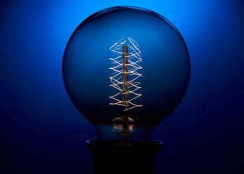 Electric vintage Edison light bulb with a spiral on a blue background. Retro style lamp.