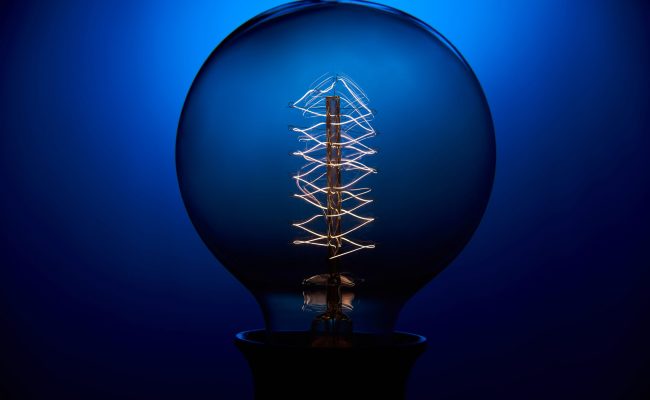 Electric vintage Edison light bulb with a spiral on a blue background. Retro style lamp.